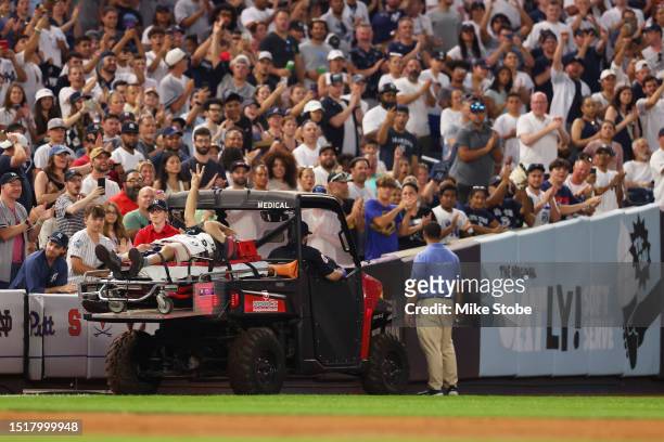 Camera man waves to the crowd as he is carted off the field after getting hit by an errant throw in the fifth inning during the game between the New...