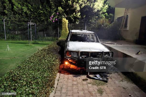 Burnt out vehicle sits smoldering in flames after it was set on fire inside the US consulate compound in Benghazi late on September 11, 2012. An...