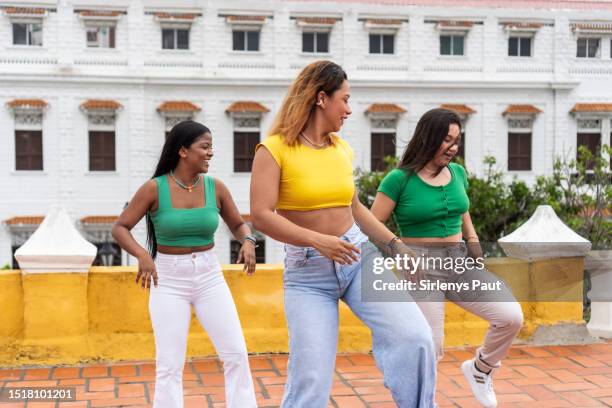 young friends dancing in the street with a building in the background. - amigos baile stockfoto's en -beelden