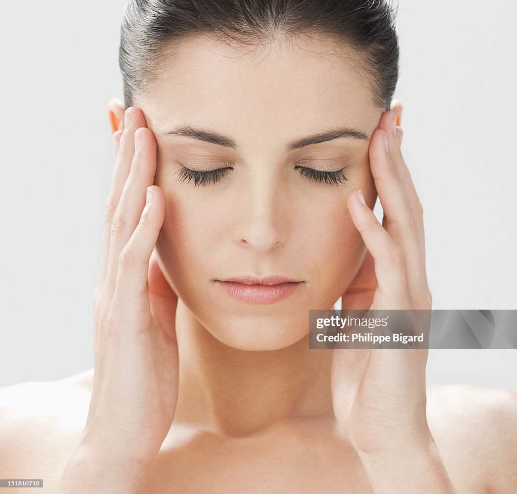 Close up of woman with head in hands and eyes closed