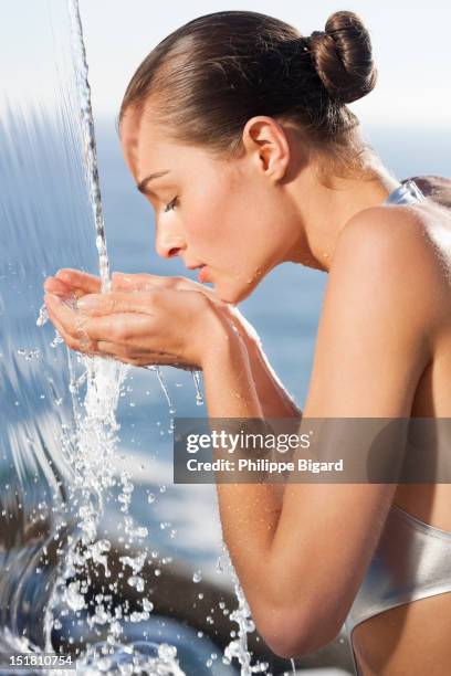 close up of woman cupping hands under waterfall - mwanzoleo stock pictures, royalty-free photos & images