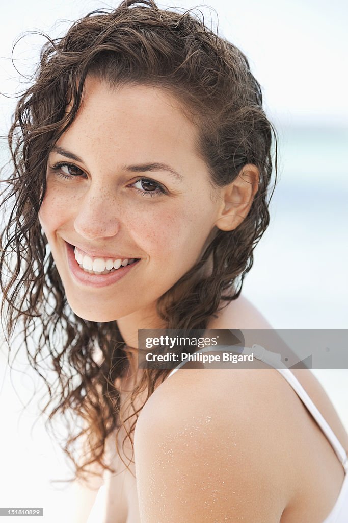 Close up portrait of smiling woman with wet hair on beach