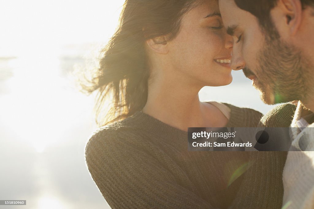 Sun shining behind couple hugging with eyes closed