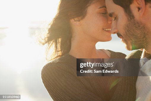 Sun shining behind couple hugging with eyes closed Sun shining behind couple hugging with eyes closed