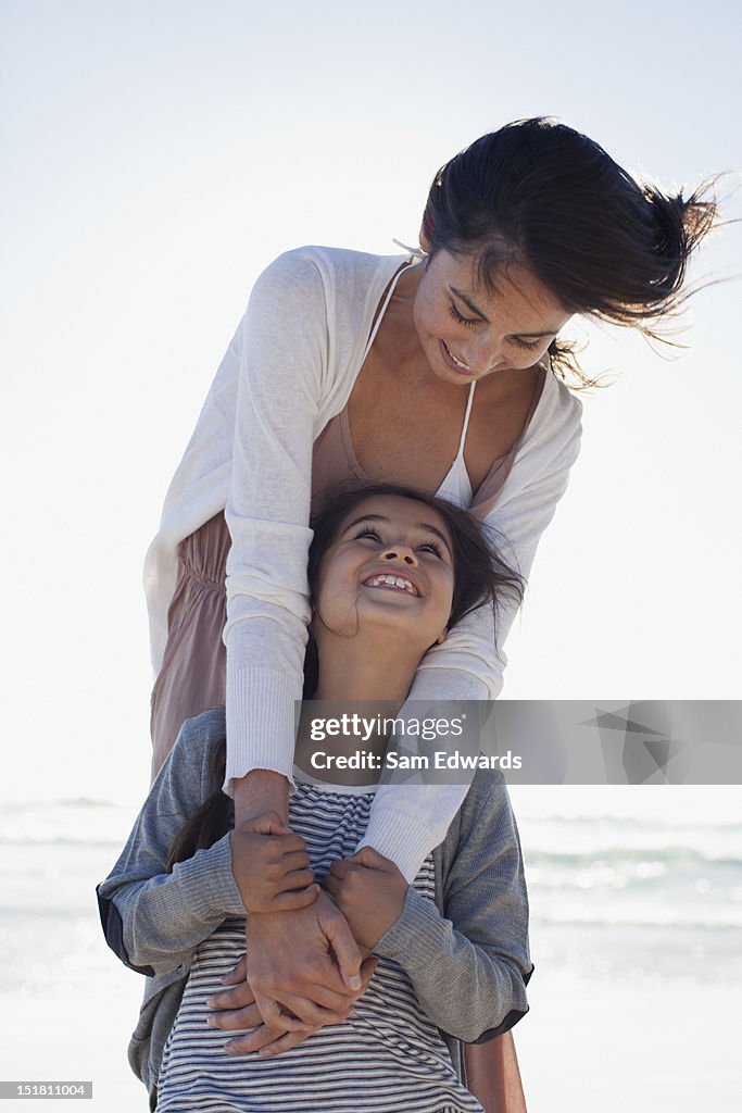 Mother and daughter hugging on sunny beach