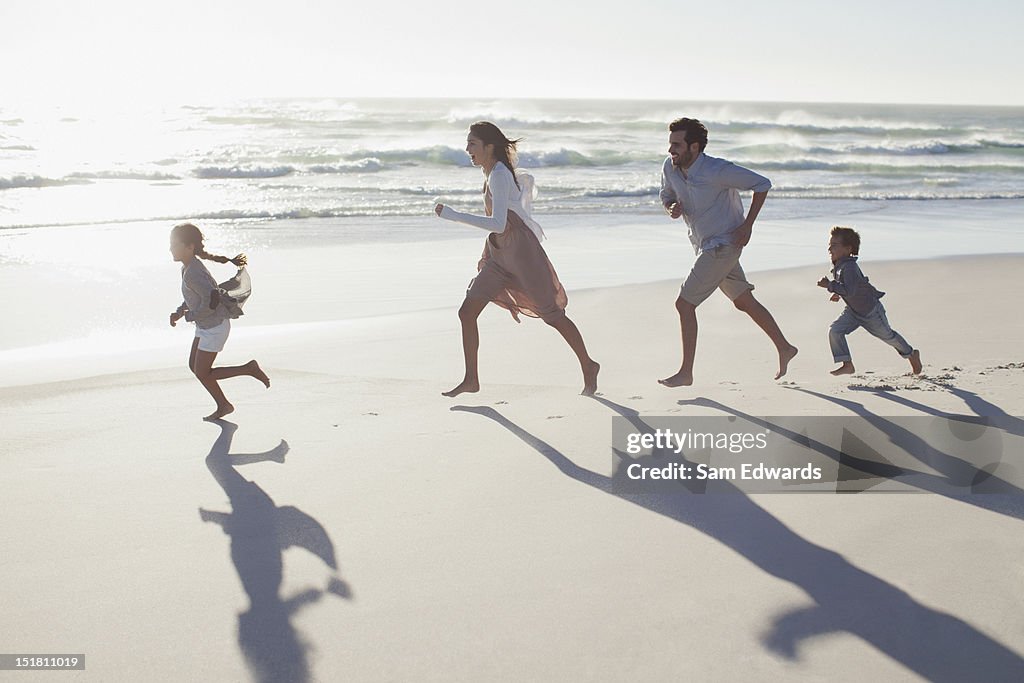 Family running on sunny beach