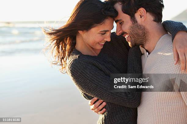 smiling couple hugging on beach - casal romântico imagens e fotografias de stock