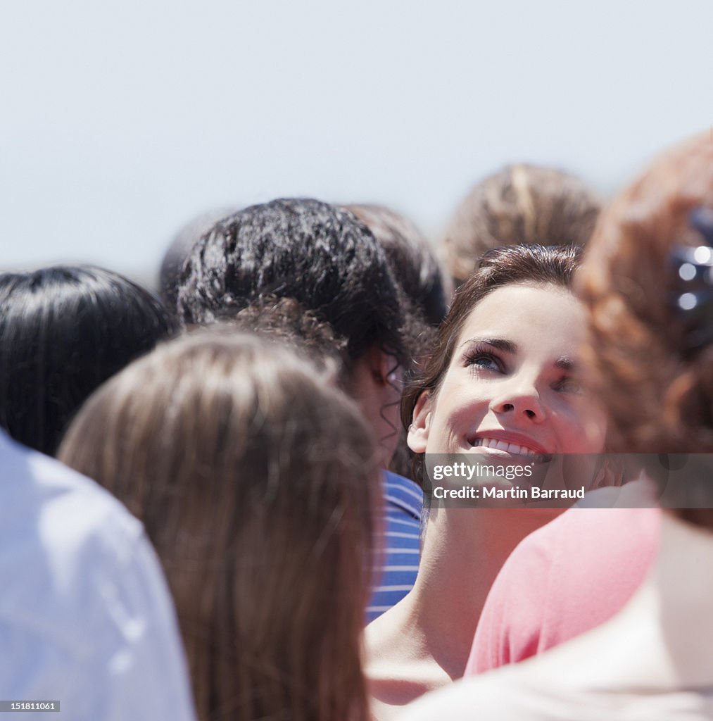 Smiling woman looking up in crowd