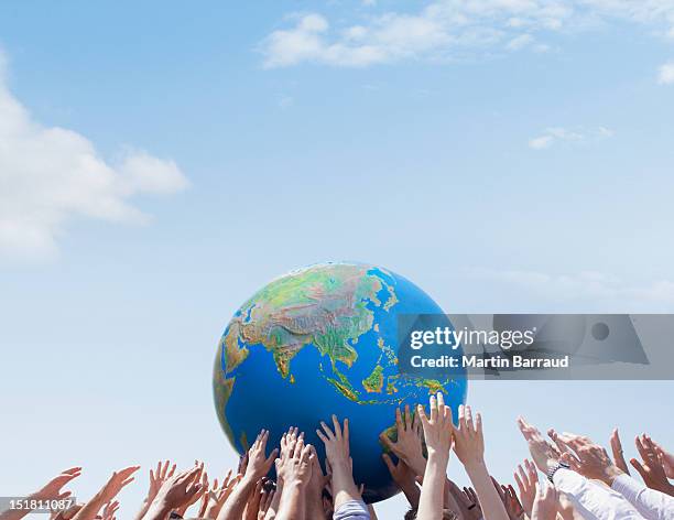 crowd reaching for globe - global diversity stock pictures, royalty-free photos & images