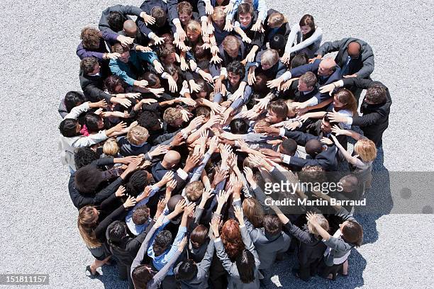 crowd of business people forming huddle with extended arms - dedication stock pictures, royalty-free photos & images