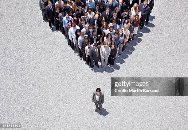 businesswoman at apex of crowd - standing out from the crowd stock pictures, royalty-free photos & images