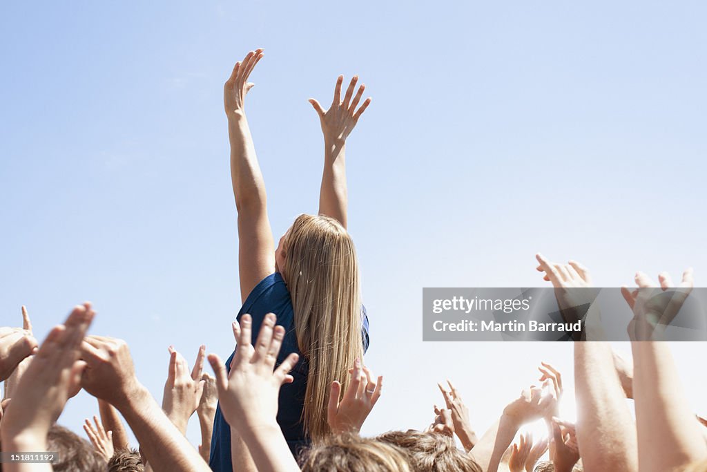 Woman with arms raised above crowd