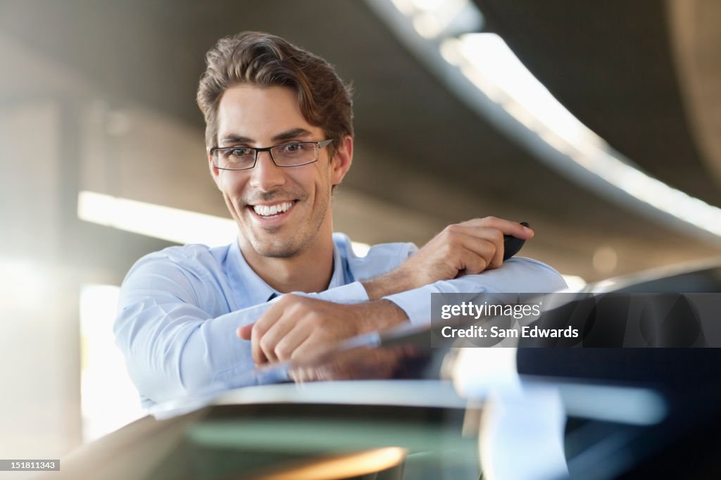 Portrait of smiling businessman leaning on car