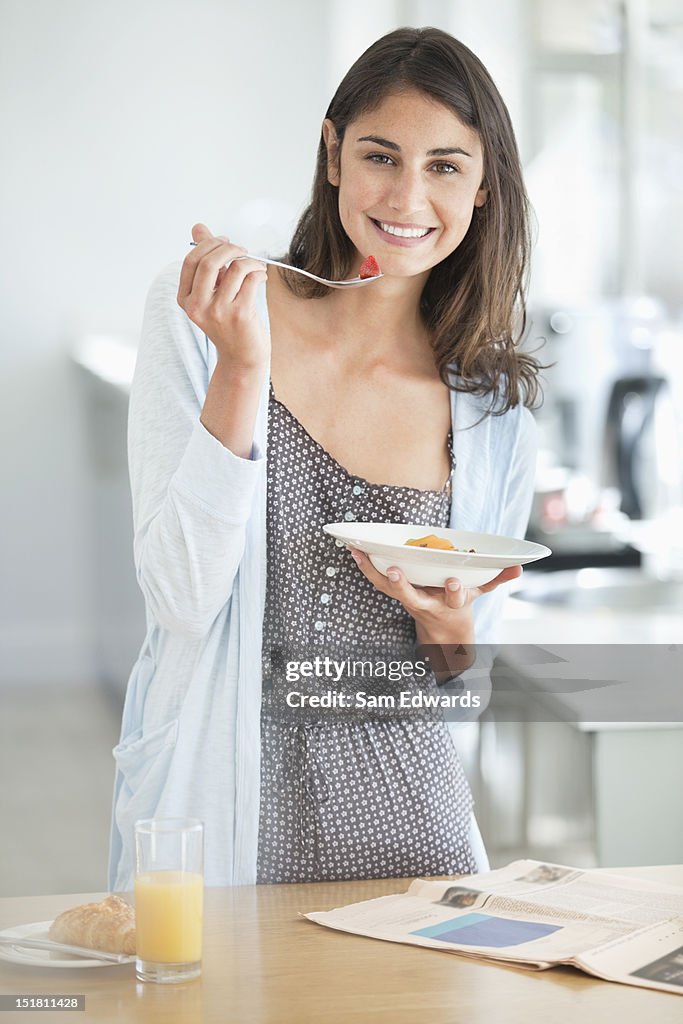 Porträt eines lächelnden Frau Essen Frühstück und Zeitung lesen