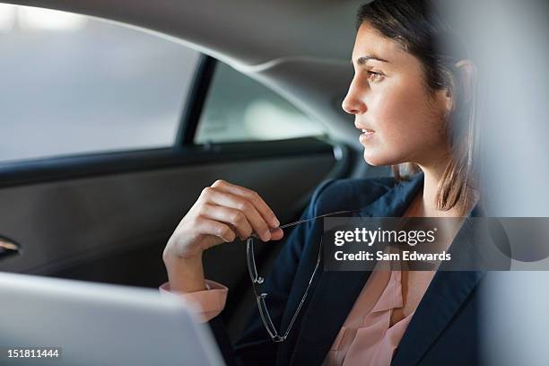 pensativo mujer de negocios con computadora portátil en el asiento de atrás de automóviles - bien vestido fotografías e imágenes de stock