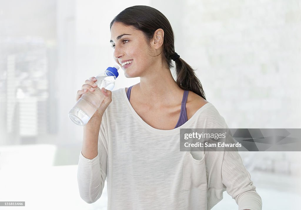 Smiling woman drinking from water bottle