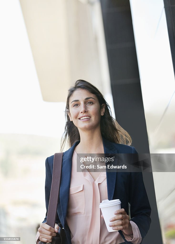 Lächelnd Geschäftsfrau zu Fuß mit Kaffeetasse