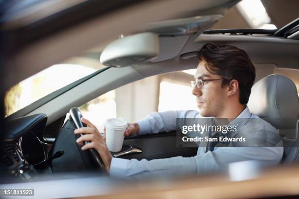 businessman holding coffee cup and driving car - business person driving stockfoto's en -beelden