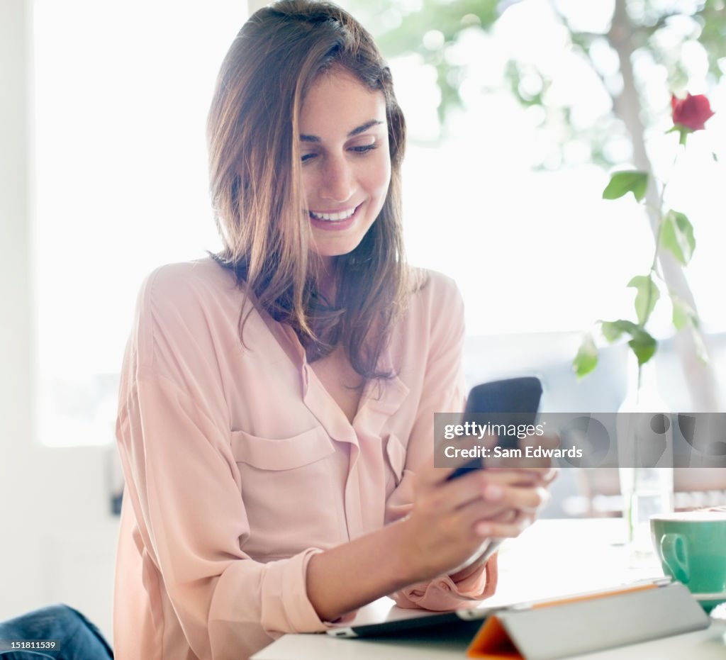 Smiling businesswoman checking cell phone