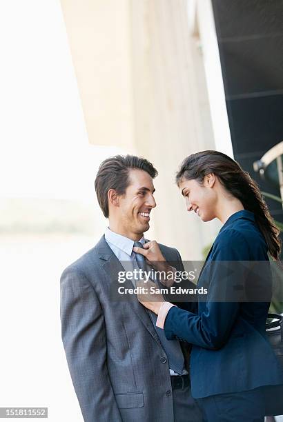 smiling businesswoman adjusting businessmans tie - ties stock pictures, royalty-free photos & images