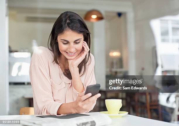 smiling businesswoman looking down at cell phone in cafe window - receiving text stock pictures, royalty-free photos & images