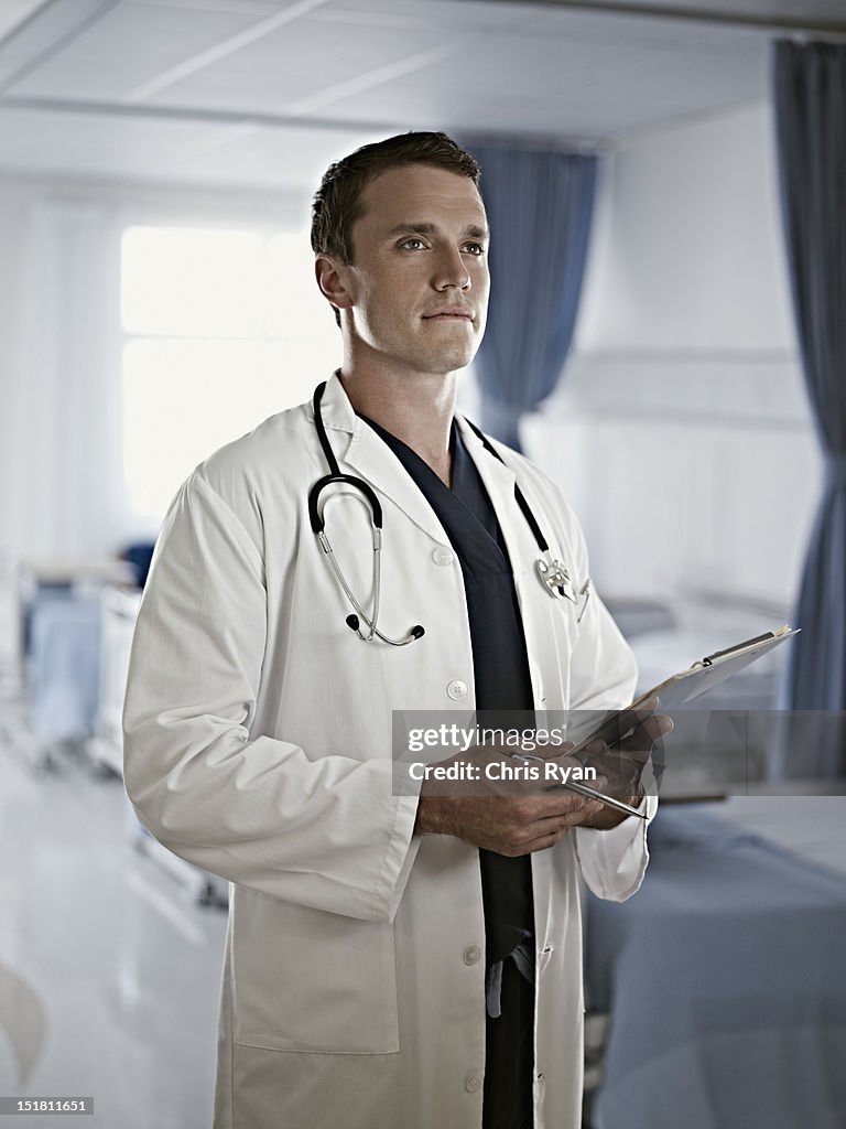 Portrait of confident doctor holding medical record in hospital room
