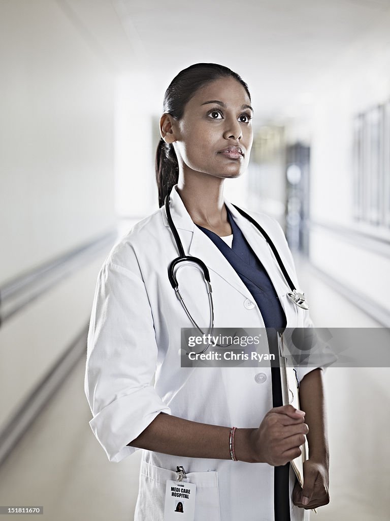 Portrait of pensive doctor holding medical record in hospital corridor