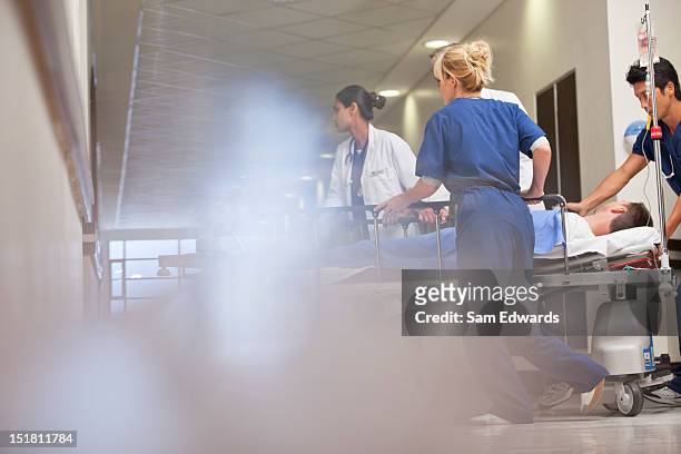 doctors and nurses wheeling patient in - notaufnahme stock-fotos und bilder