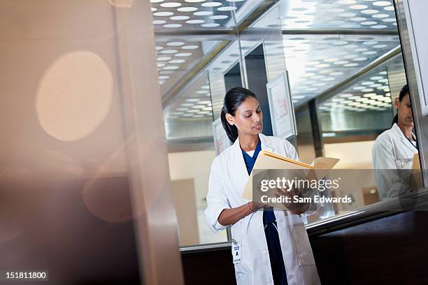 doctor revisando registro médico en hospital ascensor - informe-médico fotografías e imágenes de stock