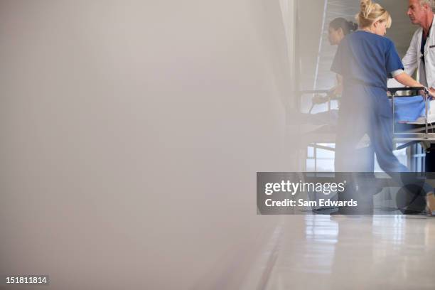 doctor and nurses wheeling patient in hospital corridor - stretcher stock pictures, royalty-free photos & images