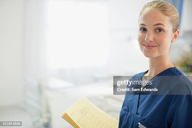 portrait of smiling nurse holding medical record in hospital room - smiling nurse stock pictures, royalty-free photos & images