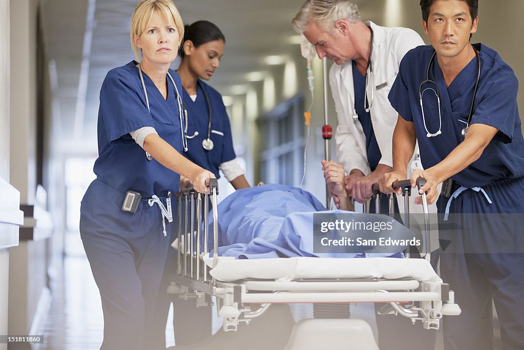 Arzt und Krankenschwestern wheeling Patienten im Krankenhaus-Rollbett down corri