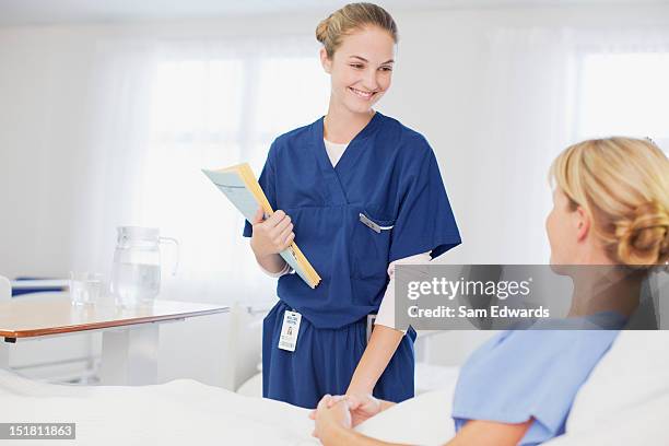 nurse with medical records talking to patient in hospital room - patient room stockfoto's en -beelden