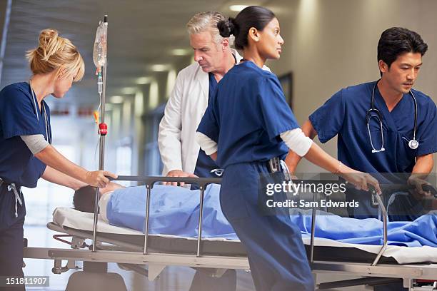 médico y enfermeras wheeling paciente en mesa de ruedas de hospital co a - hospital gurney fotografías e imágenes de stock