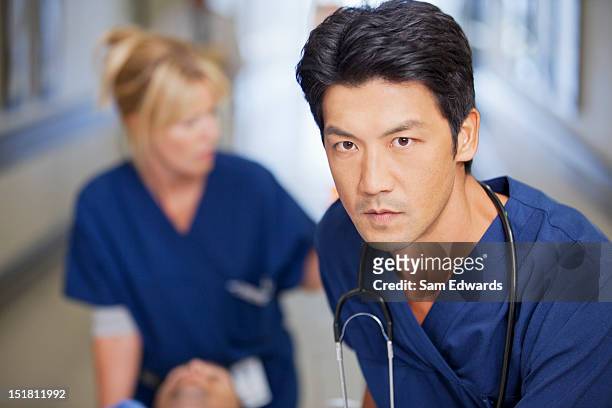 close up of serious nurse pushing patient down hospital corridor - determination doctor stock pictures, royalty-free photos & images