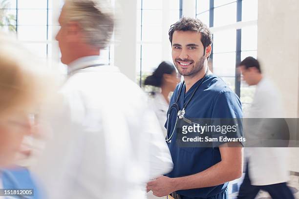 portrait of smiling nurse in hospital - busy hospital lobby stockfoto's en -beelden