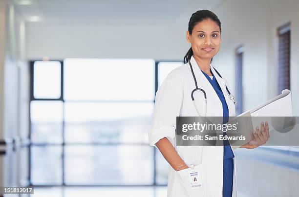 portrait of smiling doctor with notepad in hospital corridor - sjukvårdsrelaterat material bildbanksfoton och bilder