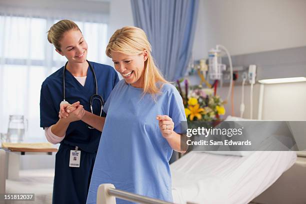 nurse helping happy patient stand in hospital room - nurse standing stock pictures, royalty-free photos & images