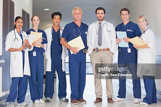 portrait of confident doctors and nurses in hospital corridor - nurse full length stock pictures, royalty-free photos & images