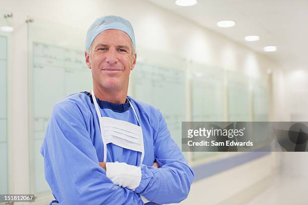 portrait of smiling surgeon in hospital corridor - surgeon stock pictures, royalty-free photos & images