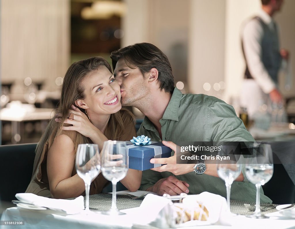 Hombre Besando a la mujer dando regalos a y en el restaurante
