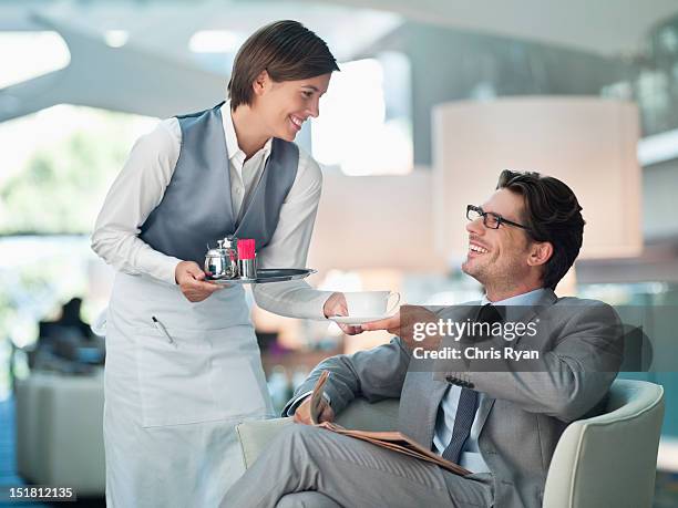 waitress serving businessman cup of coffee in hotel lounge - beverage with cream stockfoto's en -beelden