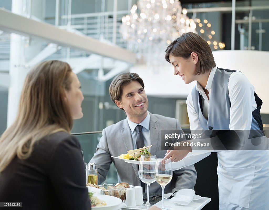 Waitress serving food to couple in restaurant