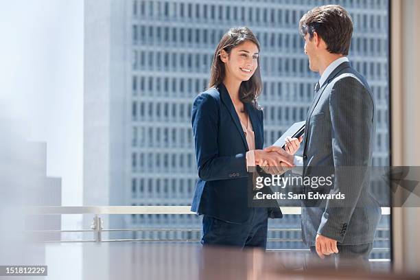 smiling businessman and businesswoman shaking hands on urban balcony - business agreement stock pictures, royalty-free photos & images