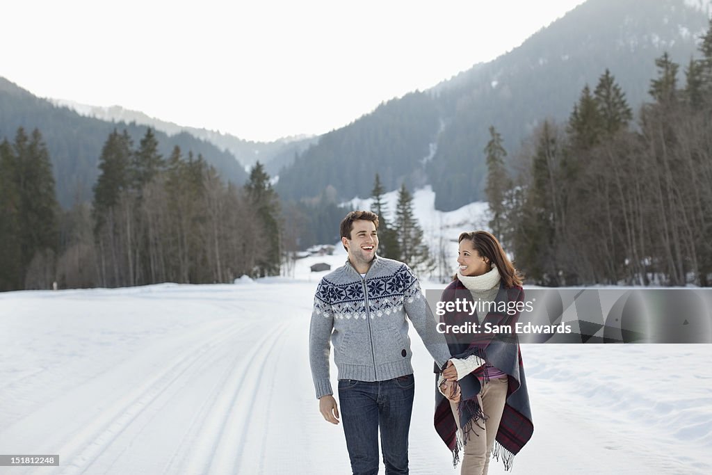 Smiling couple holding hands and walking in snowy field