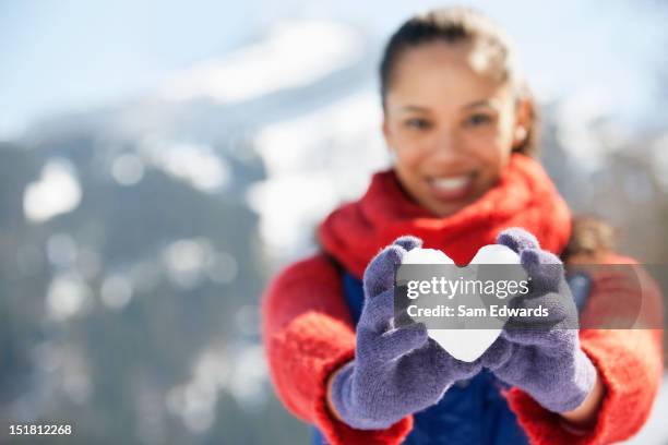 portrait of smiling woman holding heart-shape snowball - snowball stock pictures, royalty-free photos & images