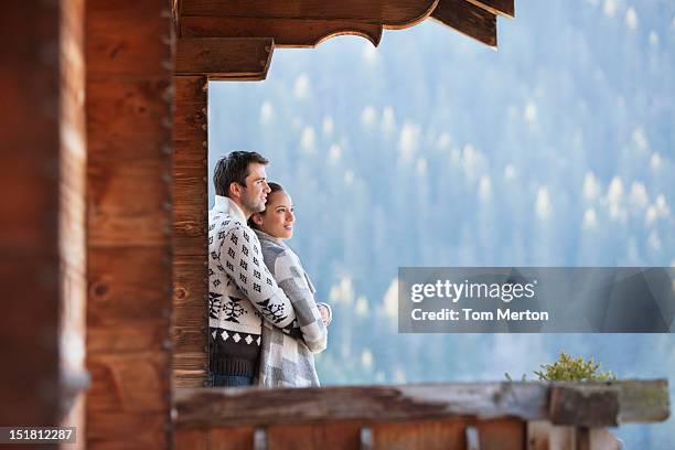 pareja abrazándose y mirando a ver desde el porche de cabina - cabaña de madera fotografías e imágenes de stock