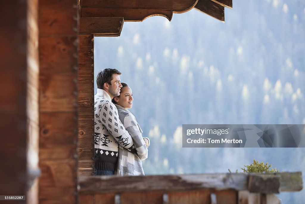 Couple hugging and looking at view from cabin porch
