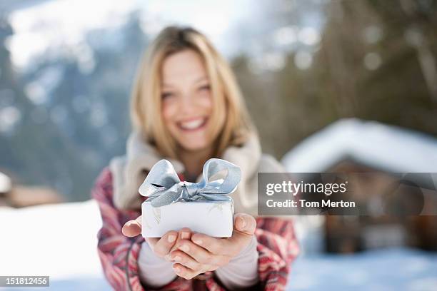 portrait of smiling woman holding christmas gift in front of cabin - winter woman showing stock pictures, royalty-free photos & images