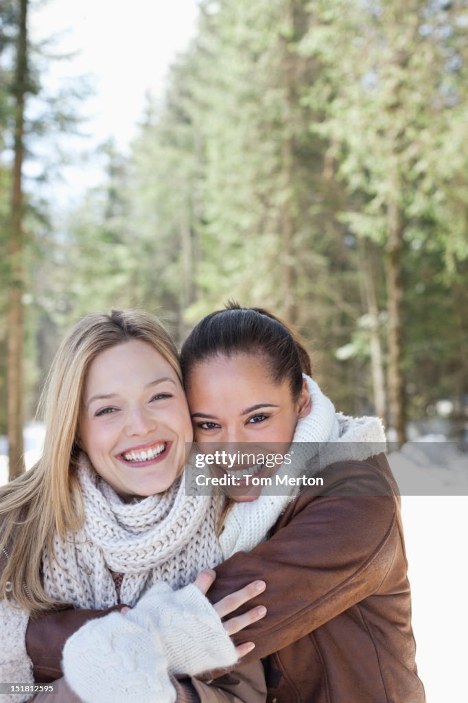 Porträt von lächelnden Freunde Umarmen in verschneiten Wald